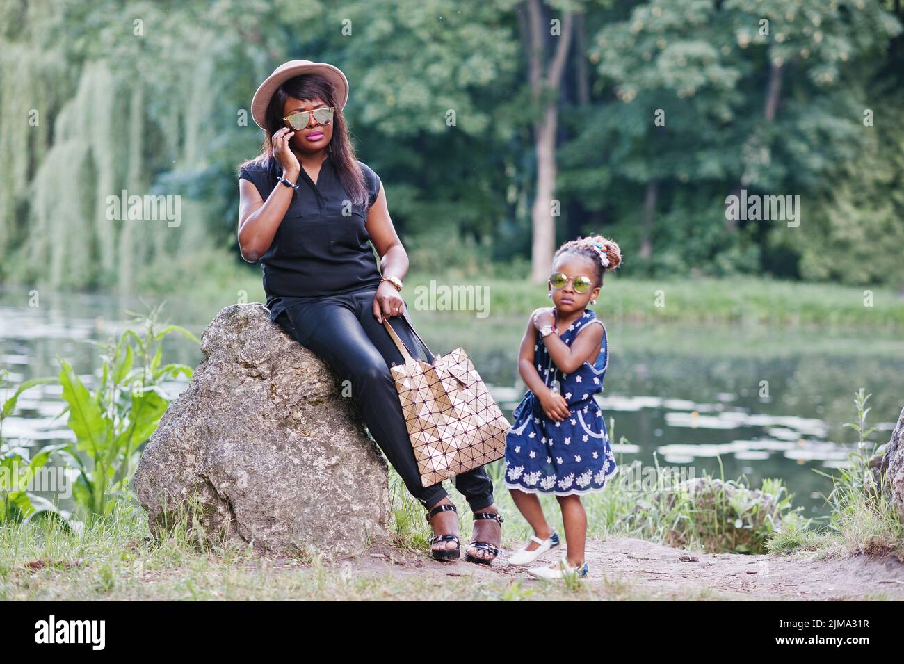 African American Style mère et fille à lunettes de soleil. Black woman with mobile phone Banque D'Images