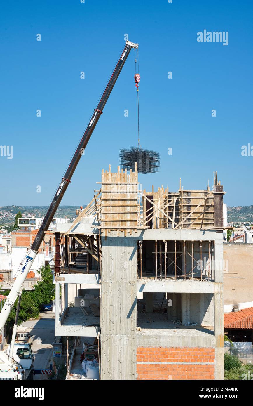 une grue automotrice extra-robuste décharge les matériaux en fer dans un bâtiment érigé Banque D'Images