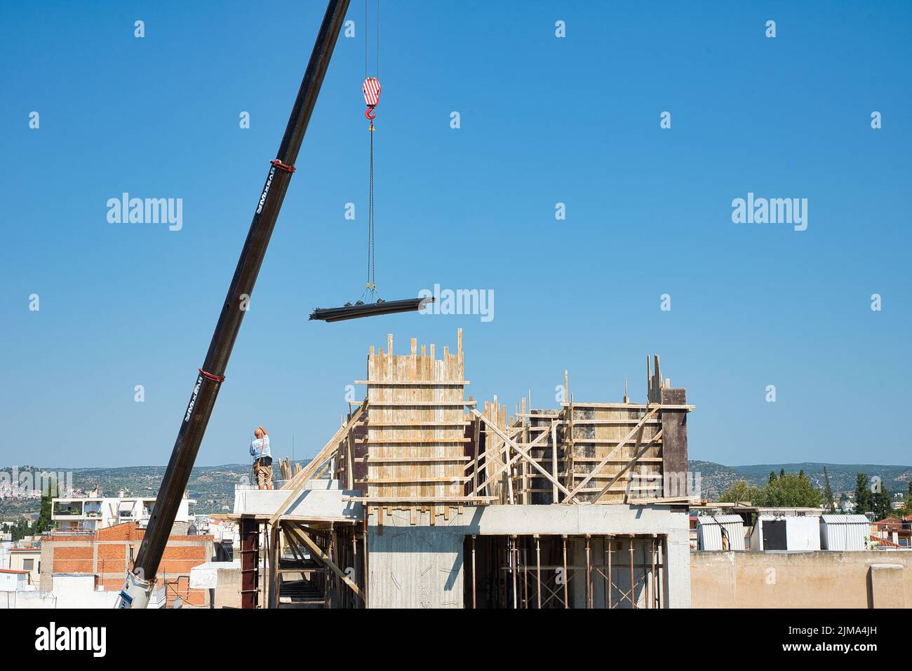 une grue automotrice extra-robuste décharge les matériaux en fer dans un bâtiment érigé Banque D'Images