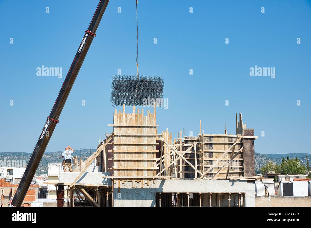 une grue automotrice extra-robuste décharge les matériaux en fer dans un bâtiment érigé Banque D'Images