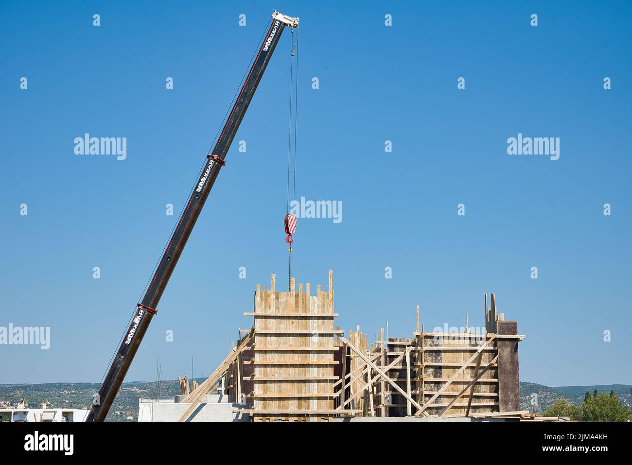 une grue automotrice extra-robuste décharge les matériaux en fer dans un bâtiment érigé Banque D'Images