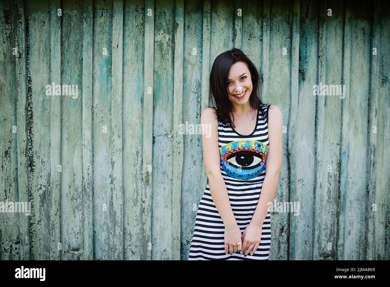 Smiling brunette model fille à s'habiller avec bandes cian fond fond de bois. Banque D'Images