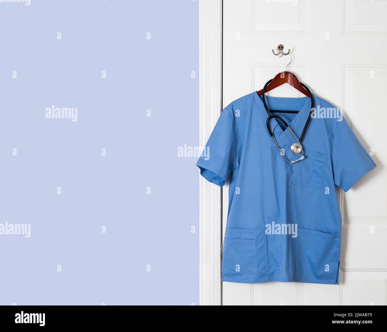 Chemise bleue pour le professionnel de la santé suspendue à la porte Banque D'Images