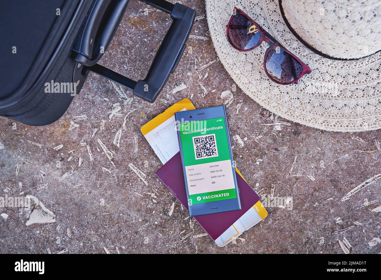 Smartphone présentant un certificat de vaccination numérique valide pour le COVID-19, une valise, un chapeau d'été, un passeport et une carte d'embarquement. Vaccination et santé pas Banque D'Images