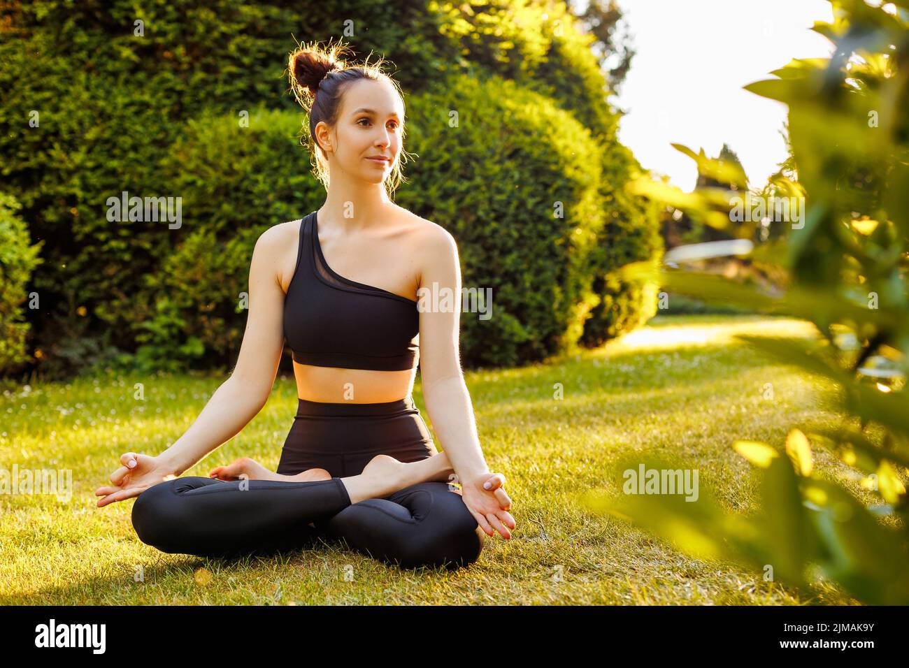 Jeune femme paisible assise dans lotus poser, respirer et méditer. Concept de yoga en plein air, relaxation, zen et équilibre mental. Belle yogini Banque D'Images