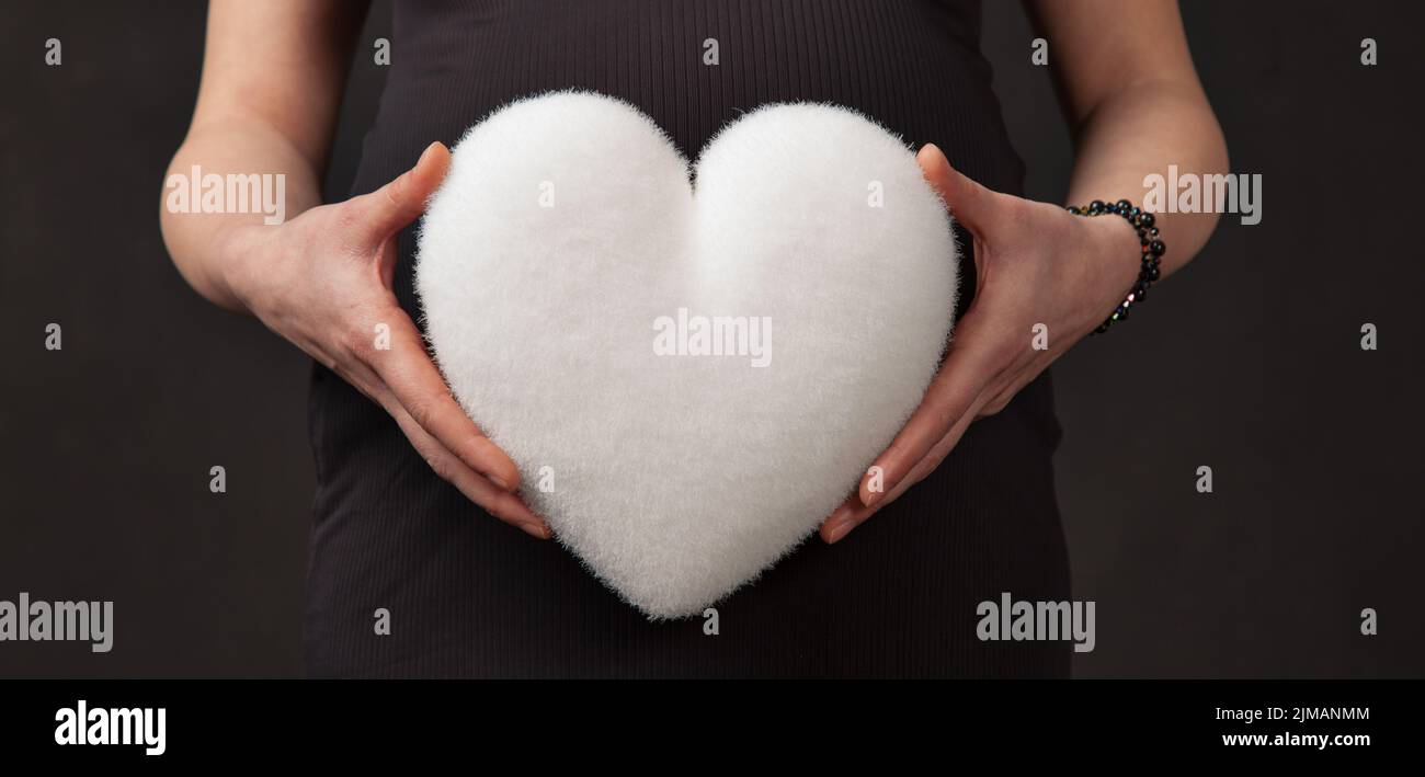 La grossesse abdomen blanc coeur mains Banque D'Images