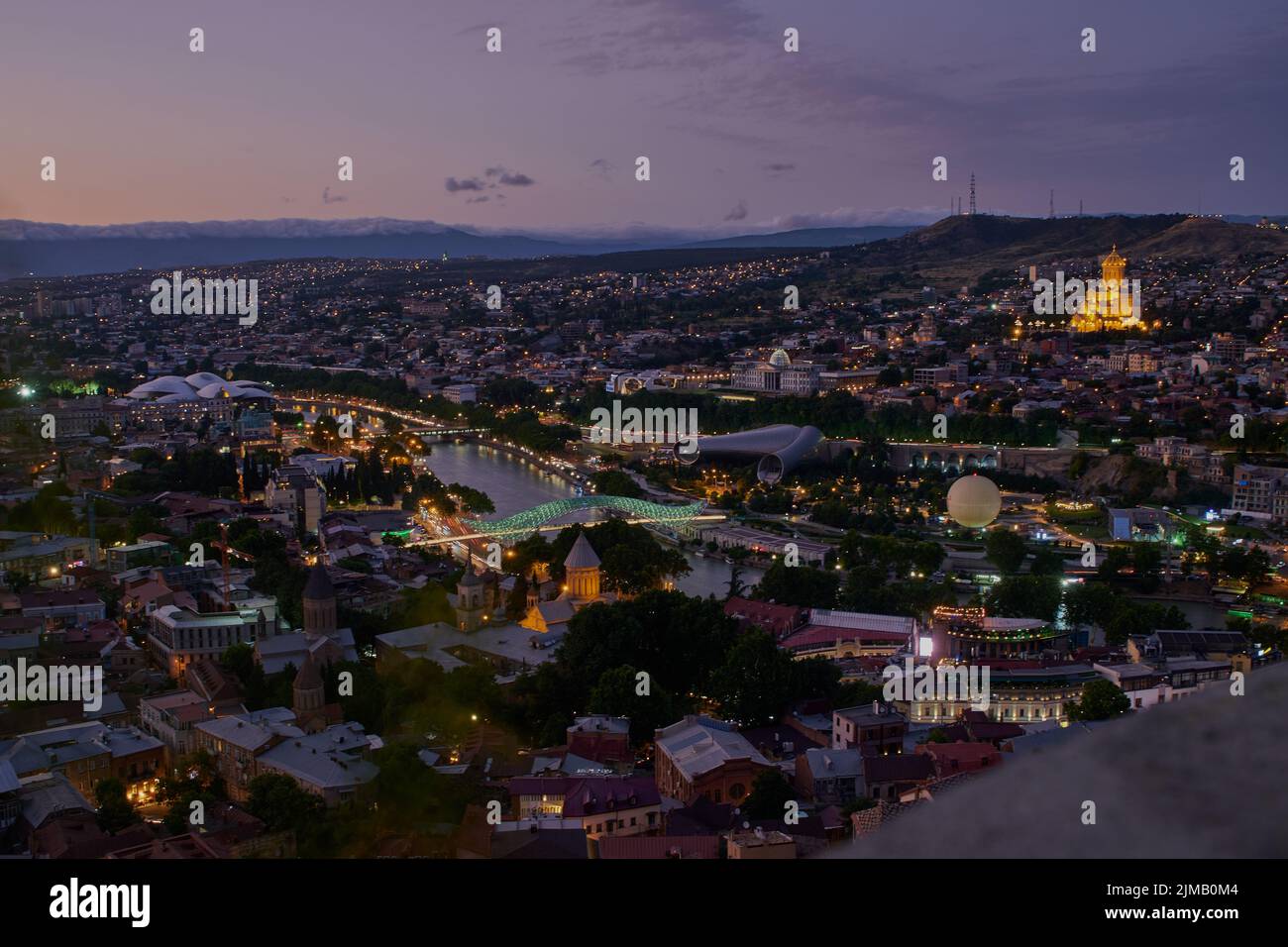 Tbilissi, Géorgie nuit vue panoramique depuis le sommet de la forteresse de Narikala montrant le pont de la paix, le parc Rike, la rivière Kura et la cathédrale Sainte-Trinité Banque D'Images