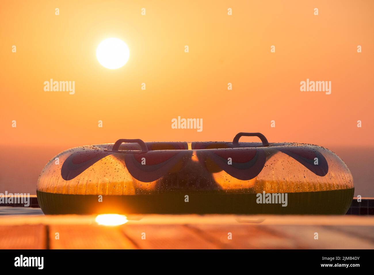 Anneau de bain gonflable sur une piscine terrasse donnant sur la mer avec Soleil Pomos Banque D'Images