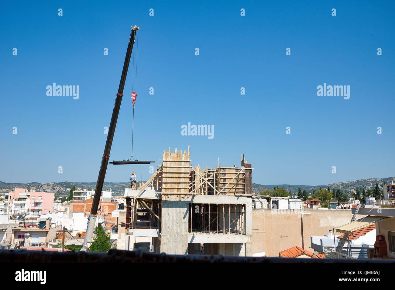 une grue automotrice extra-robuste décharge les matériaux en fer dans un bâtiment érigé Banque D'Images