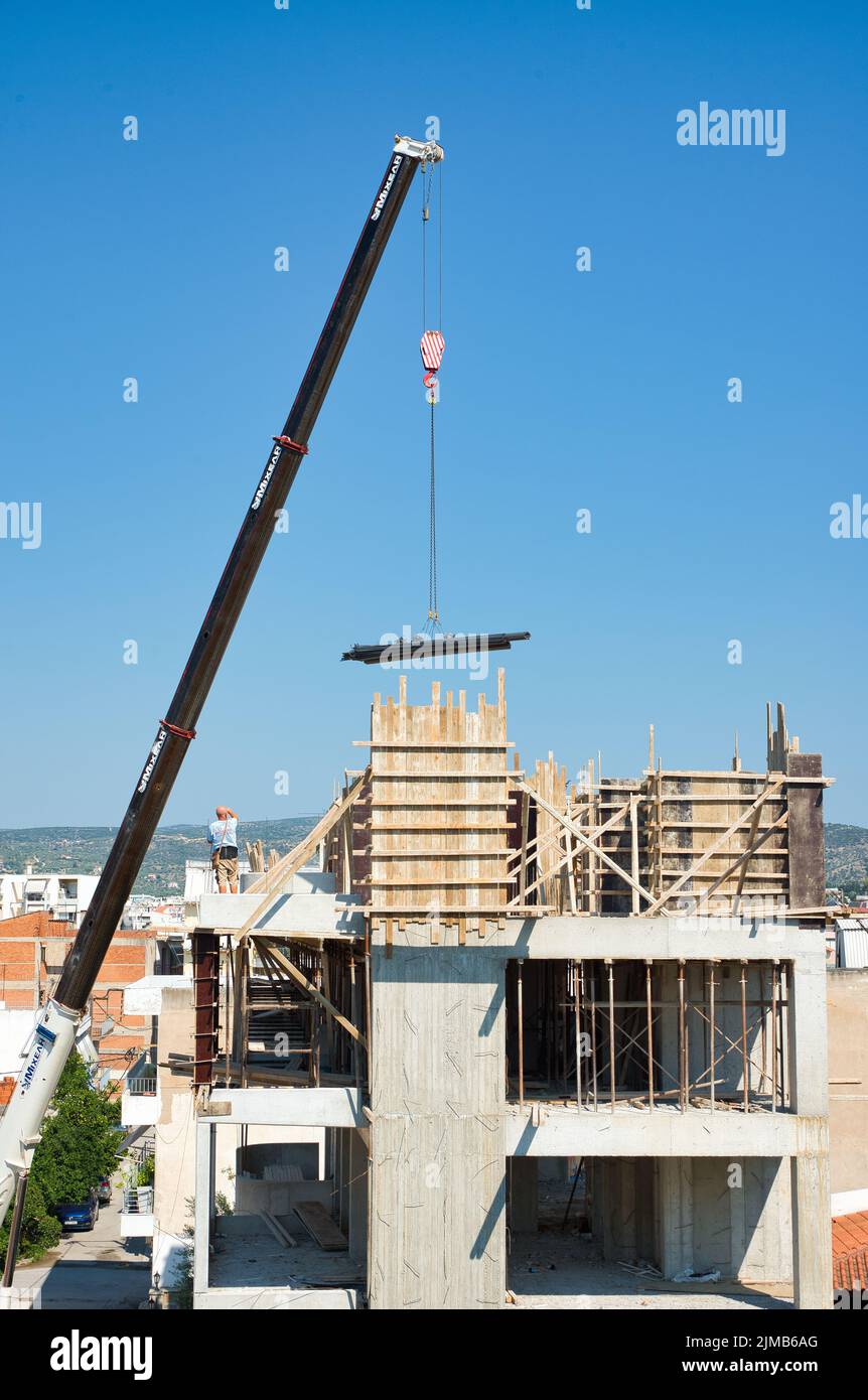 une grue automotrice extra-robuste décharge les matériaux en fer dans un bâtiment érigé Banque D'Images