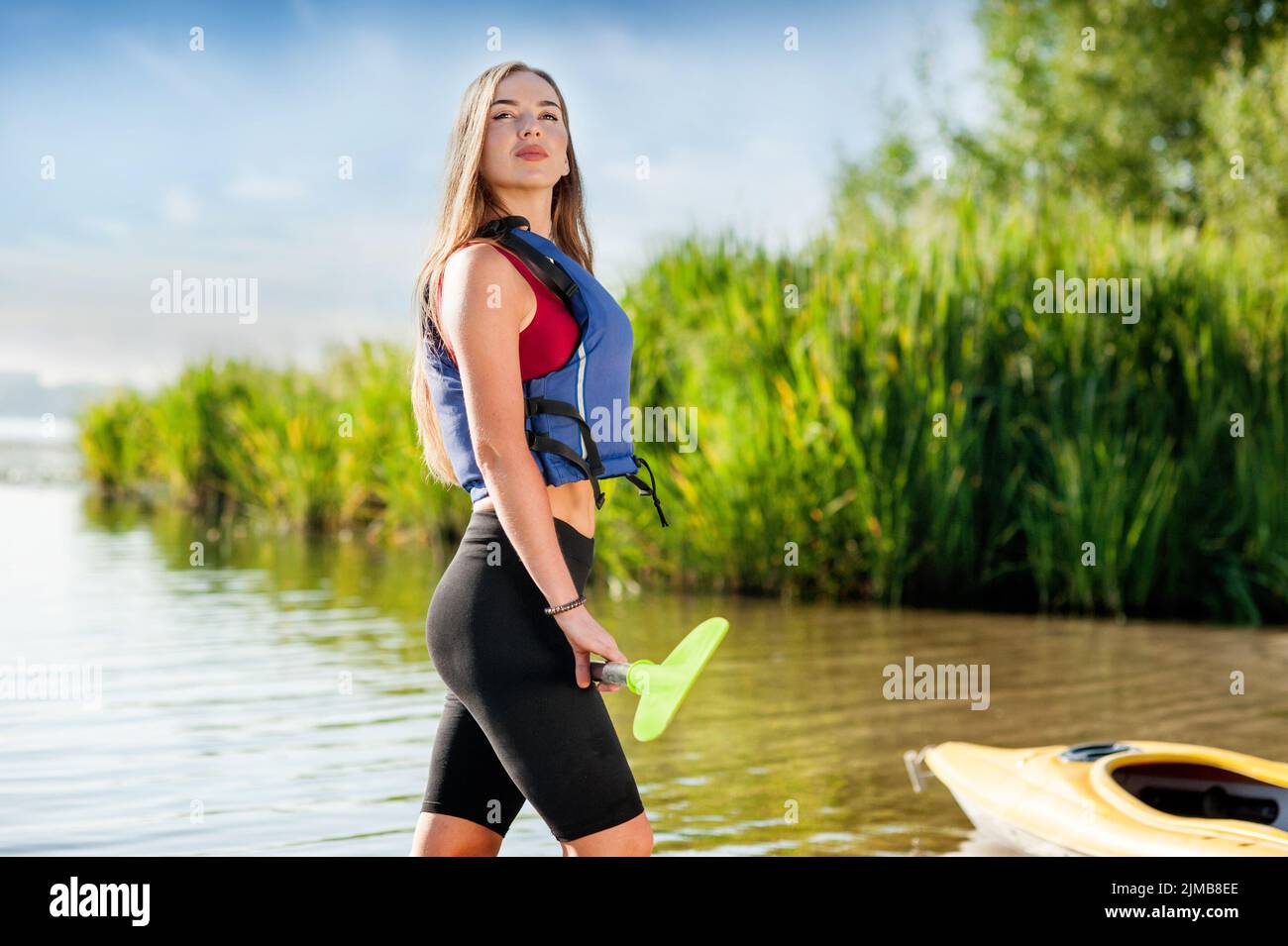 une jeune fille avec un oar et dans un gilet de vie est prête à aller kayak Banque D'Images