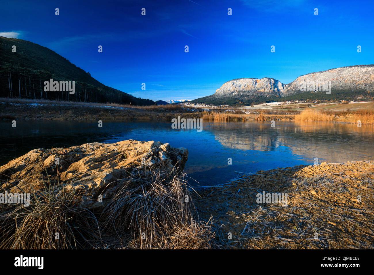 Magnifique paysage avec de hautes roches avec des pics illuminés, des pierres dans le lac de montagne, reflet, ciel bleu et lumière du soleil jaune dedans Banque D'Images