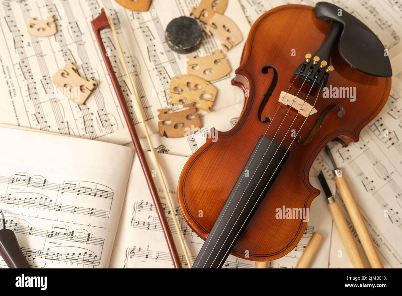 Vue de dessus d'un arc et d'un violon avec des outils et des feuilles de musique dans un atelier Banque D'Images