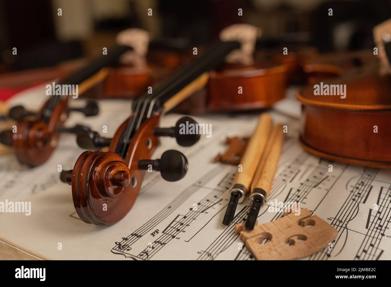 Violons au-dessus de la musique de feuille dans un atelier de réparation avec différents outils Banque D'Images