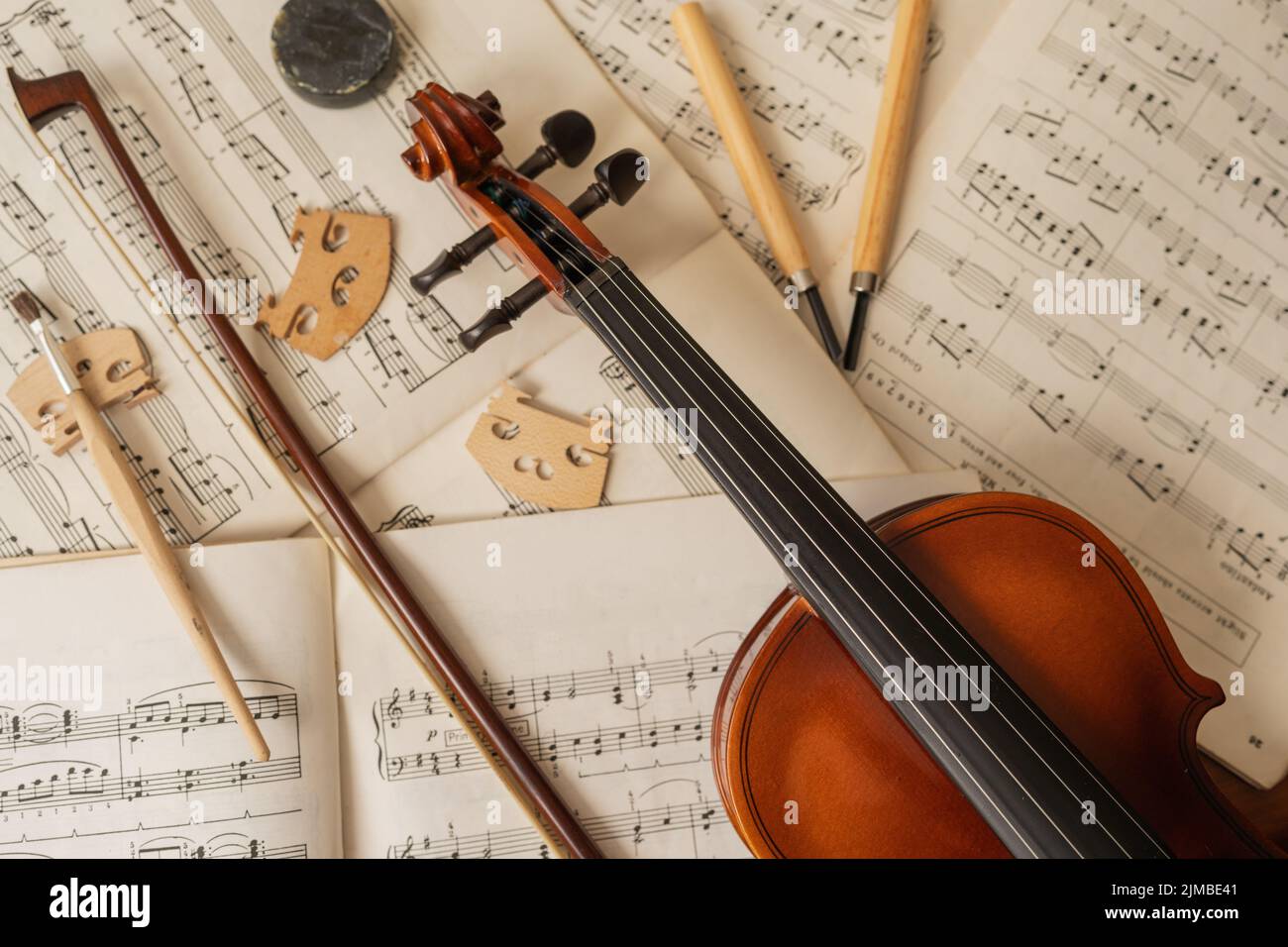 Vue de dessus d'un violon et d'un arc sur la musique en feuilles dans un atelier de réparation d'instruments de musique Banque D'Images