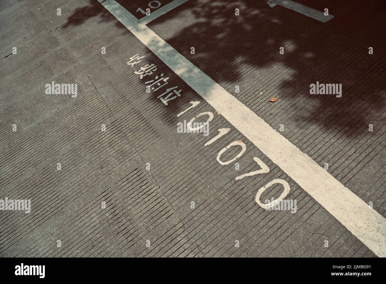 Un gros plan d'une route asphaltée avec des caractères chinois traduisant « parking payant » et des chiffres Banque D'Images