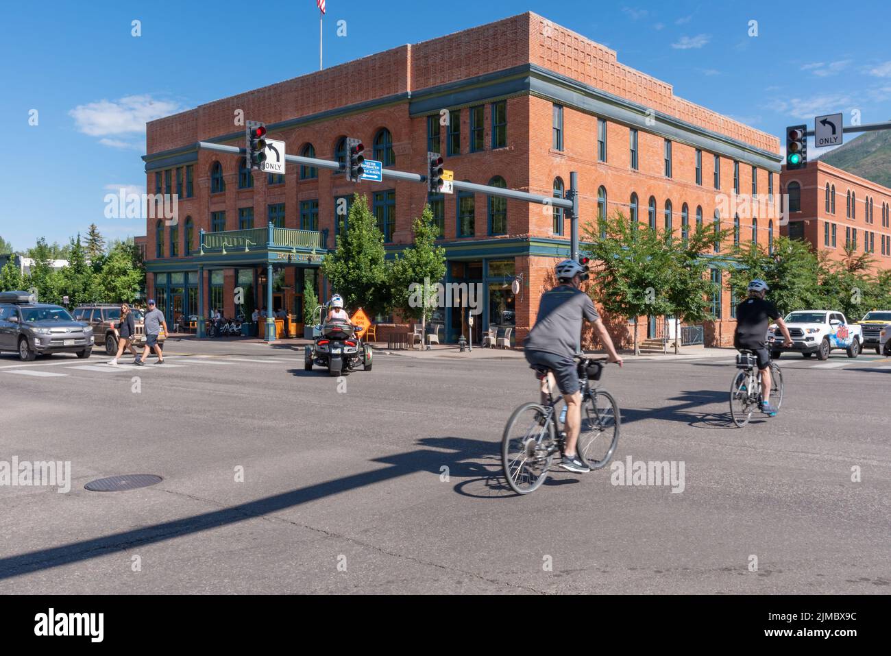 Une intersection animée avec des cyclistes, des piétons, une moto à trois roues et des voitures en face de l'hôtel Jerome à Aspen, Colorado. Banque D'Images