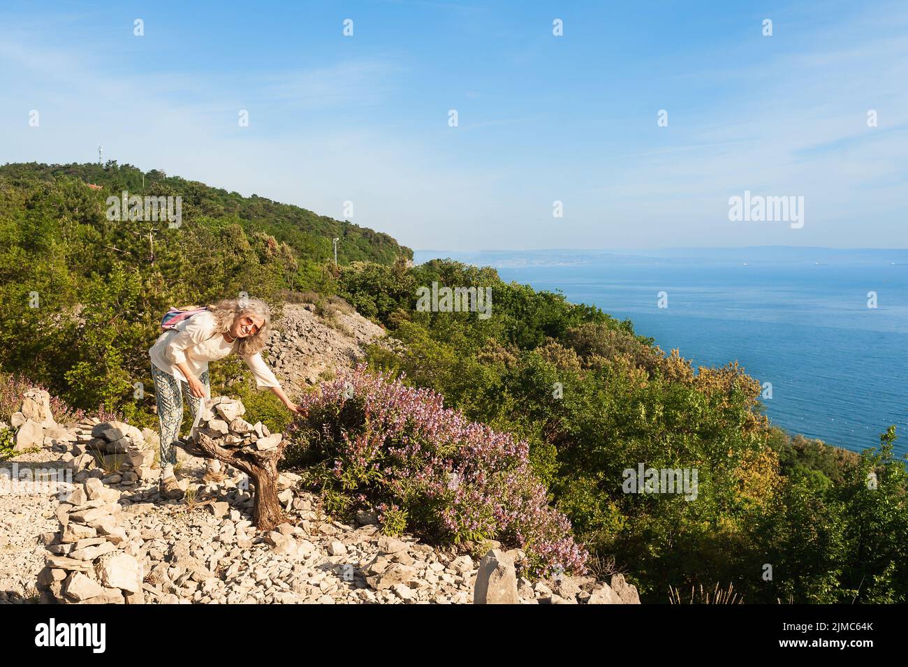 Female hiker sauge sauvage recueille sur la falaise surplombant la mer. Banque D'Images