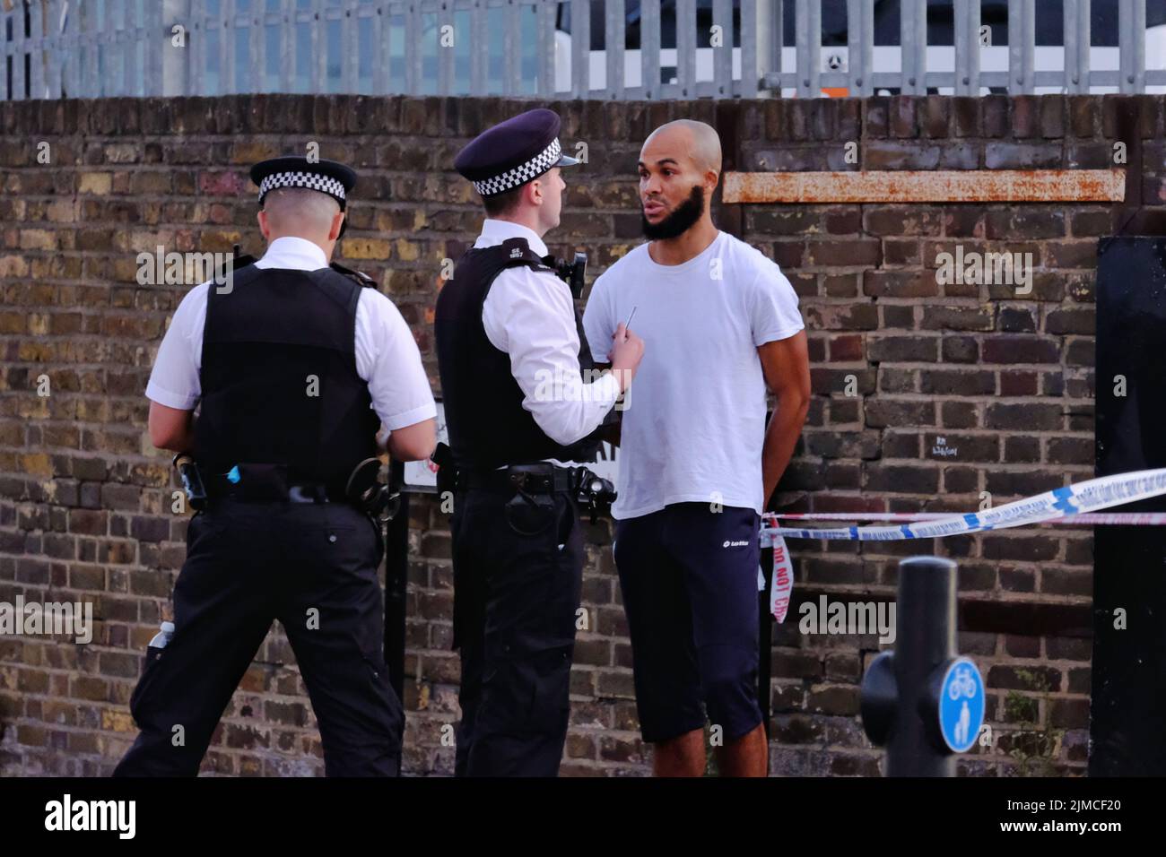 Londres, Royaume-Uni, 5th août 2022. Un jogger tente de traverser un cordon de police et est appréhendé. Les services de police ont été vus en train de travailler suite à une réponse de la police armée après avoir signalé qu'un homme portant un conduit d'arme à feu avait été fixé à la main. Après qu'un témoin oculaire ait vu un taser activé sans effet, l'homme a été abattu et traité sur place, avant d'être transporté par avion à l'hôpital. Crédit : onzième heure Photographie/Alamy Live News Banque D'Images