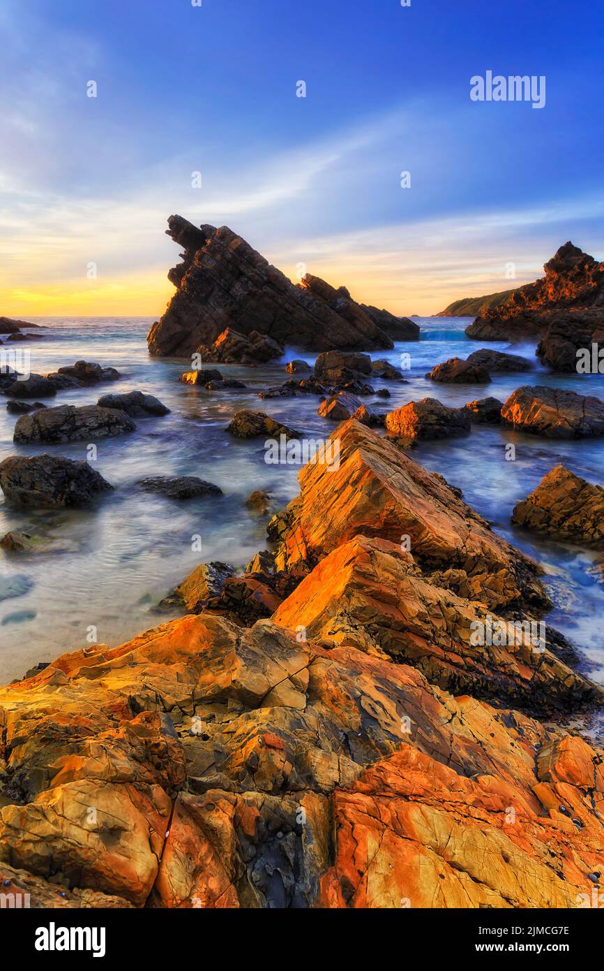 Des rochers pittoresques et colorés sur la plage de Burgess, dans la ville de Forster, en Australie, sur la côte du Pacifique, au lever du soleil. Banque D'Images