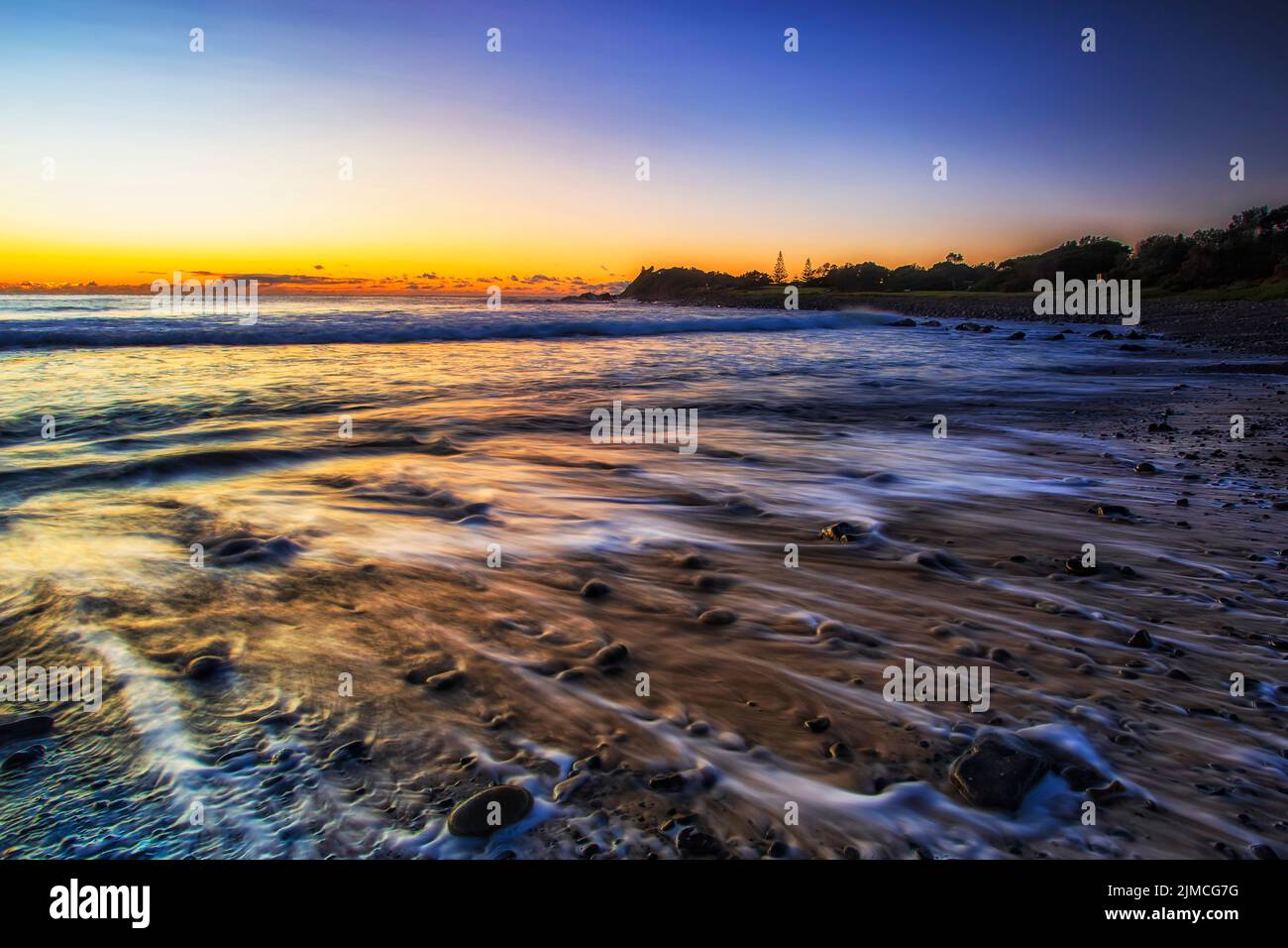 Plage de galets sur la côte Pacifique de la ville de Forster en Australie au lever du soleil - paysage marin pittoresque. Banque D'Images