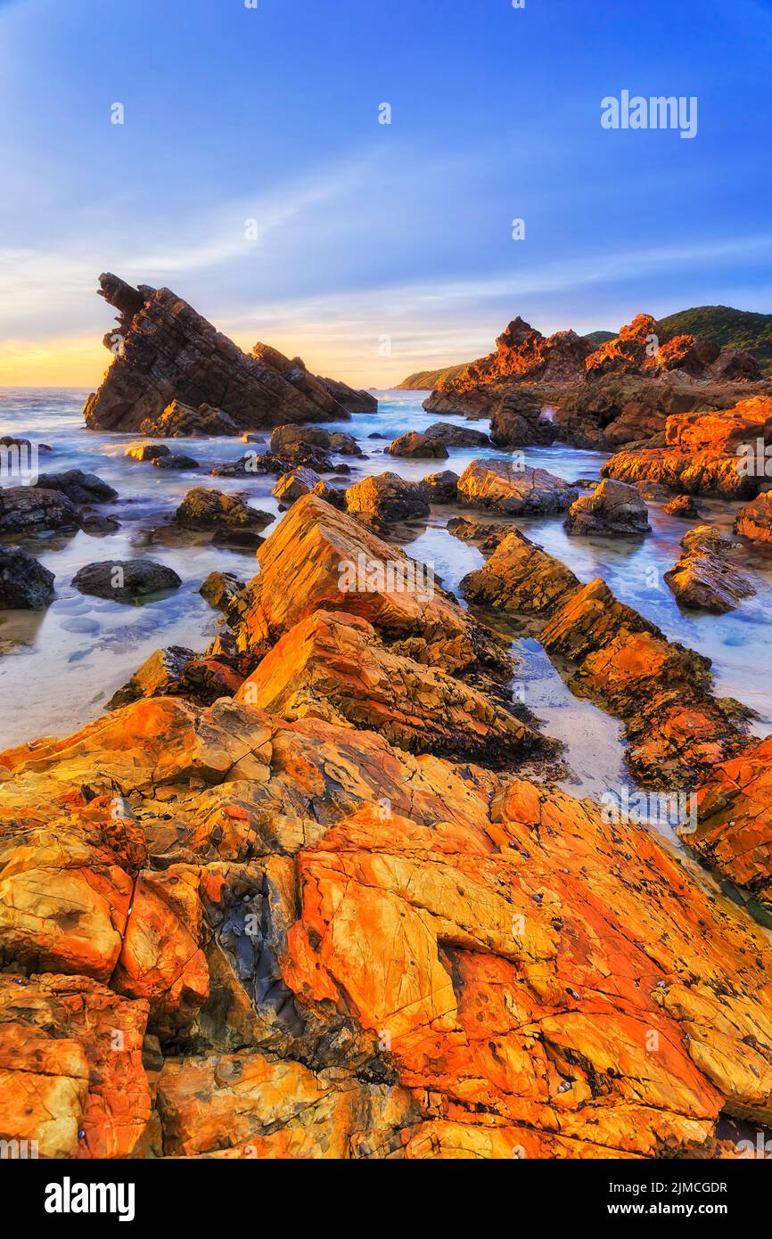 Le bazalt en grès coloré se trouve sur la plage de Burgess de la ville de Forster en Australie - côte du pacifique au lever du soleil. Banque D'Images