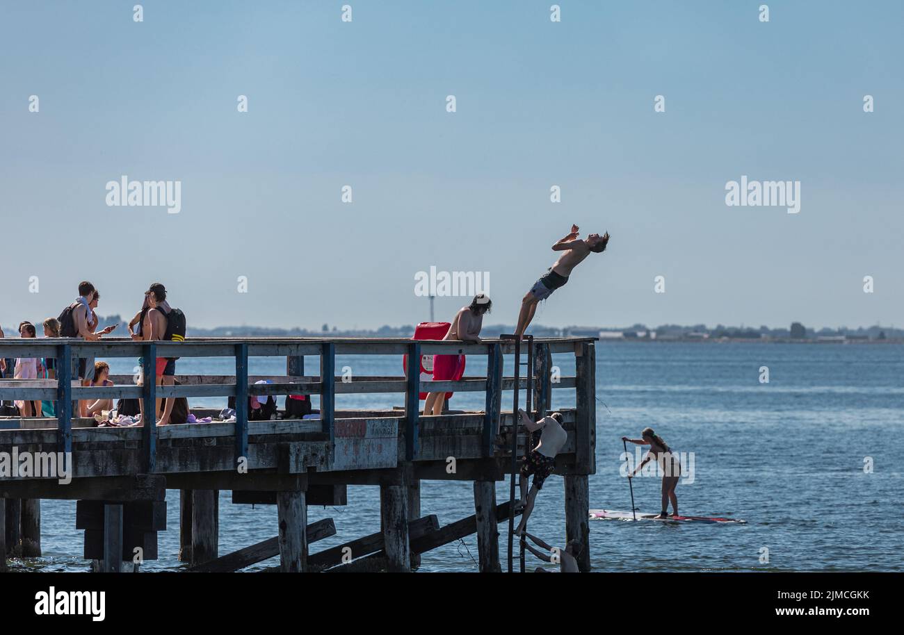 Des adolescents sautant sur une jetée en bois par une journée d'été. Saut dans la mer depuis une jetée en bois sur une plage. Happy Summer Vacation concept-White Rock BC ca Banque D'Images