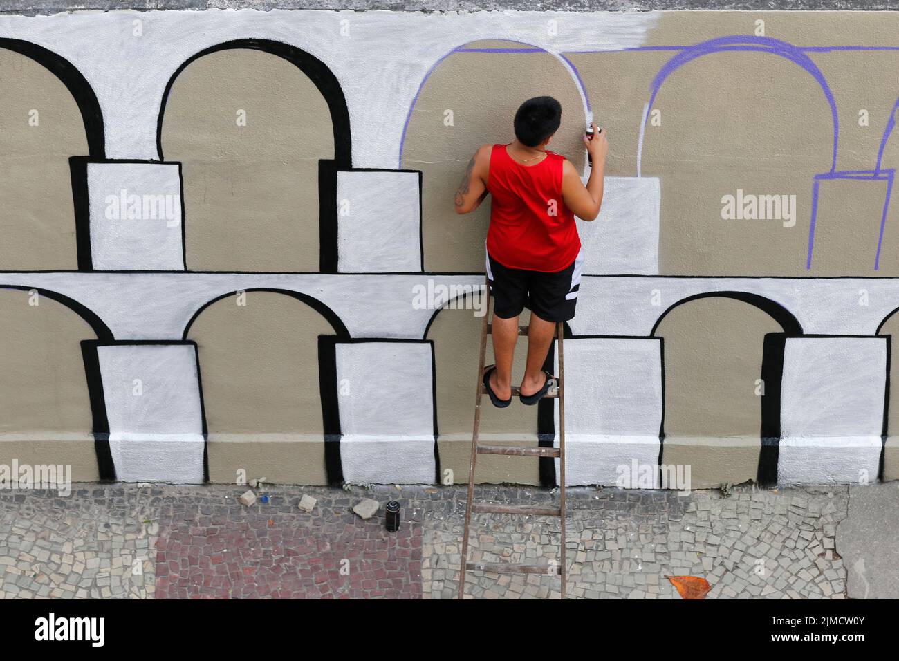 Homme peint graffiti mural d'Arcos da Lapa. Artiste de rue créant un travail de design moderne Banque D'Images