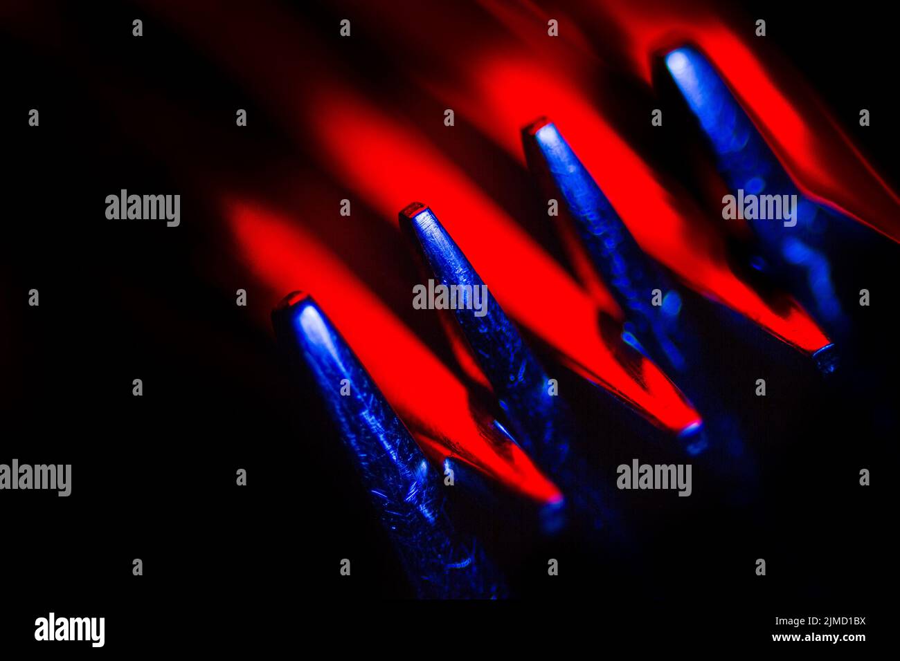 Deux fourches en éclairage coloré macro-shot créant une composition abstraite adaptée comme un arrière-plan. Banque D'Images