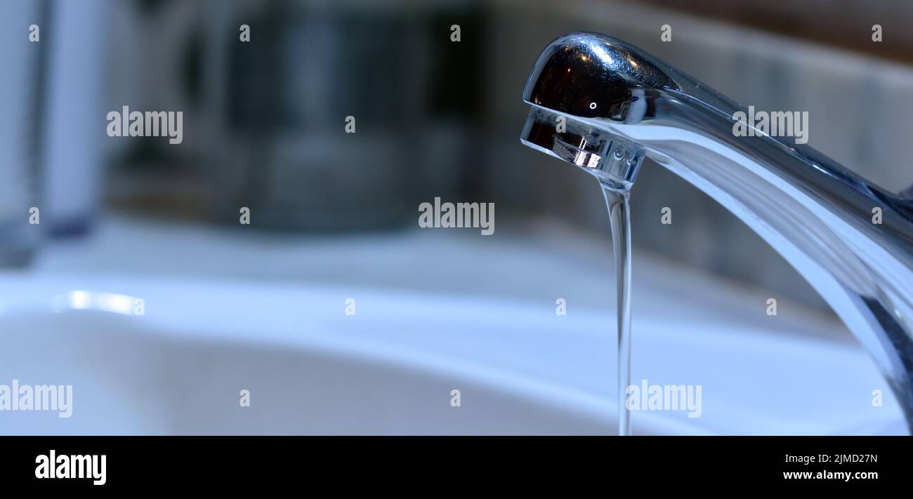 Pequeño chorro de agua cayendo de un grifo de un lavabo Banque D'Images