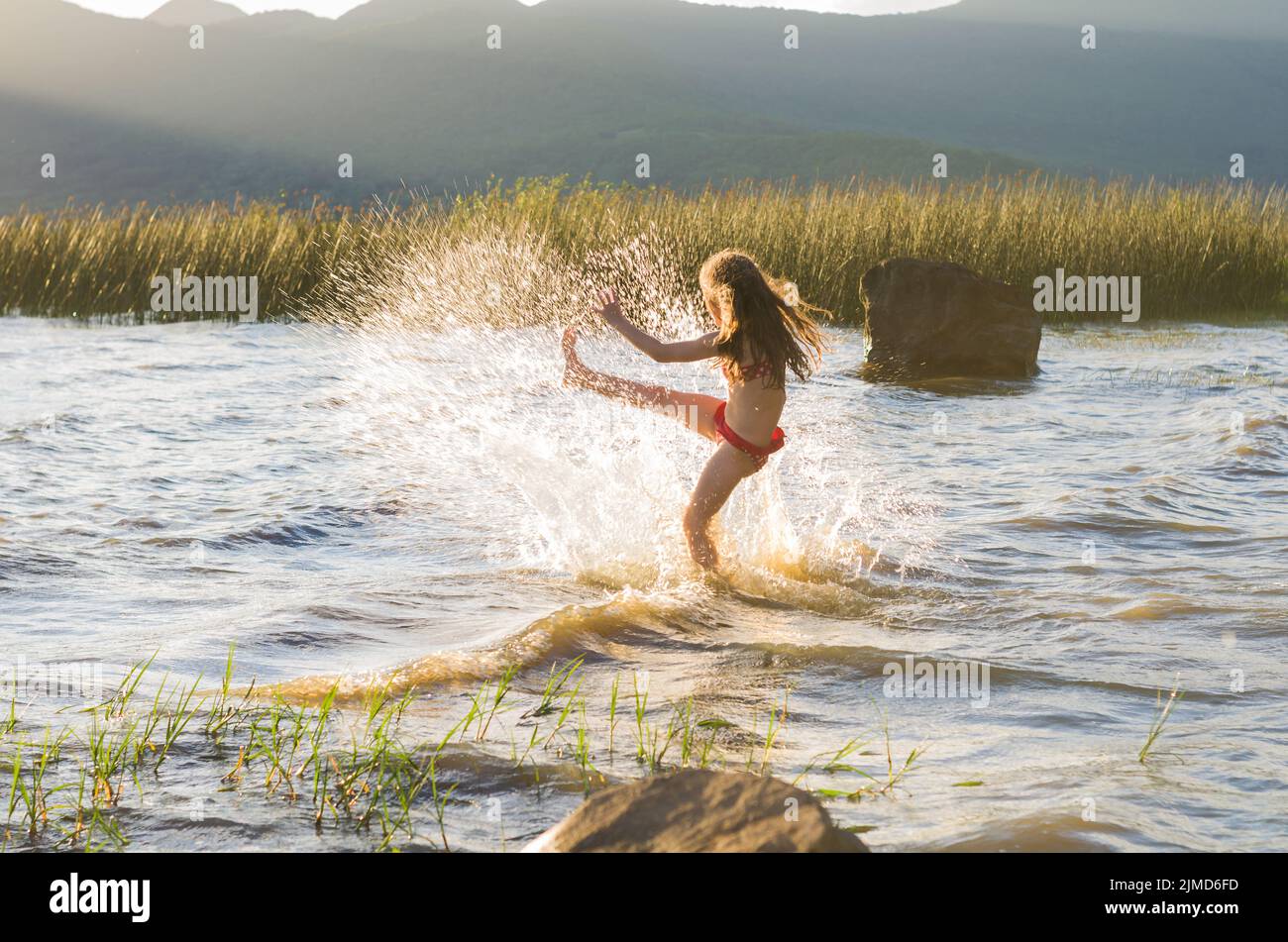 Enfant jouant dans l'eau, donnant de l'eau à coups de pied de l'étang Banque D'Images