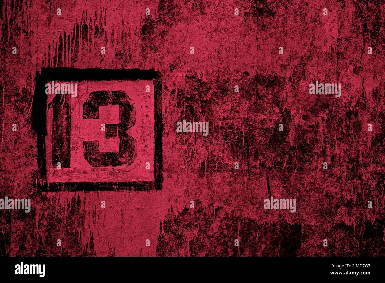 Numéro 13 peint avec un pochoir noir sur un mur en béton rouge coloré Banque D'Images