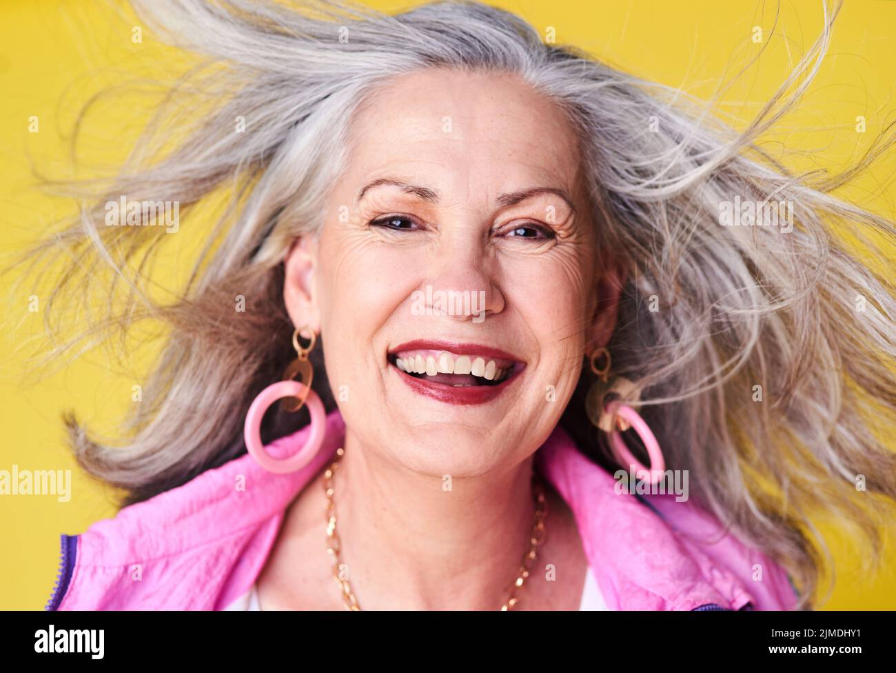 L'esprit ne doit jamais devenir vieux. Portrait d'une femme âgée gaie et élégante posant sur un fond jaune. Banque D'Images