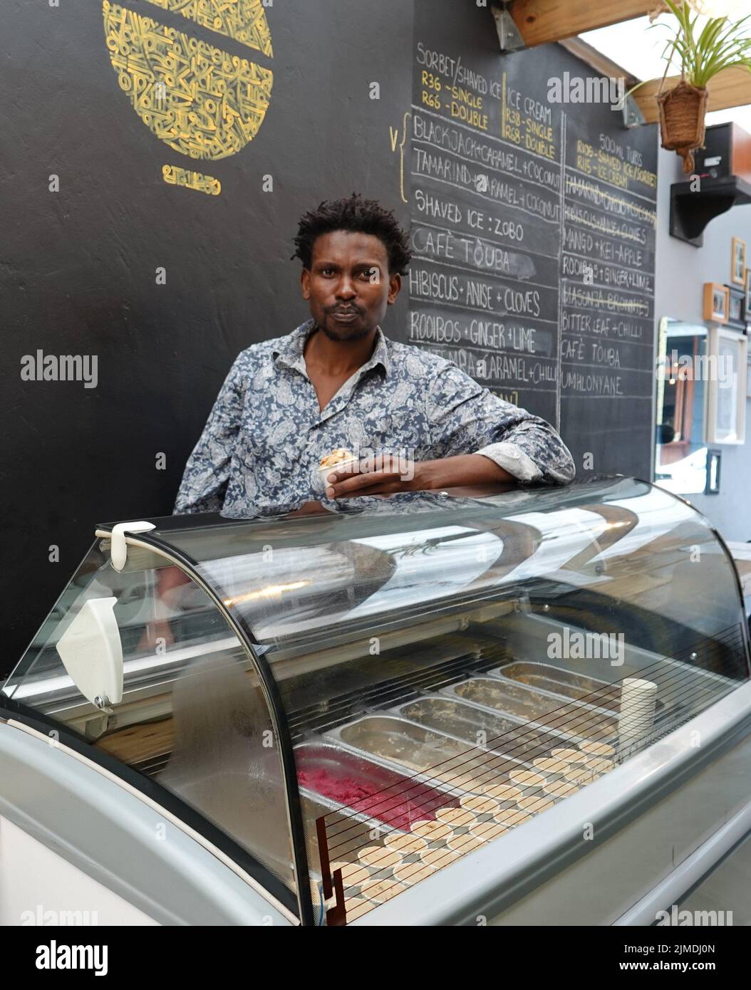Kapstadt, Afrique du Sud. 26th juillet 2022. Tapiwa Guzha se trouve dans son glacier TAPI TAPI. Le biologiste moléculaire a inventé plus de 600 variétés de glace inhabituelles dans la métropole touristique du Cap. Tapiwa Guzha aime jouer avec de nouvelles combinaisons de saveurs. (À dpa 'poisson et argile: Curieuse tendance de la glace au Cap') Credit: Kristin Palitza/dpa/Alamy Live News Banque D'Images