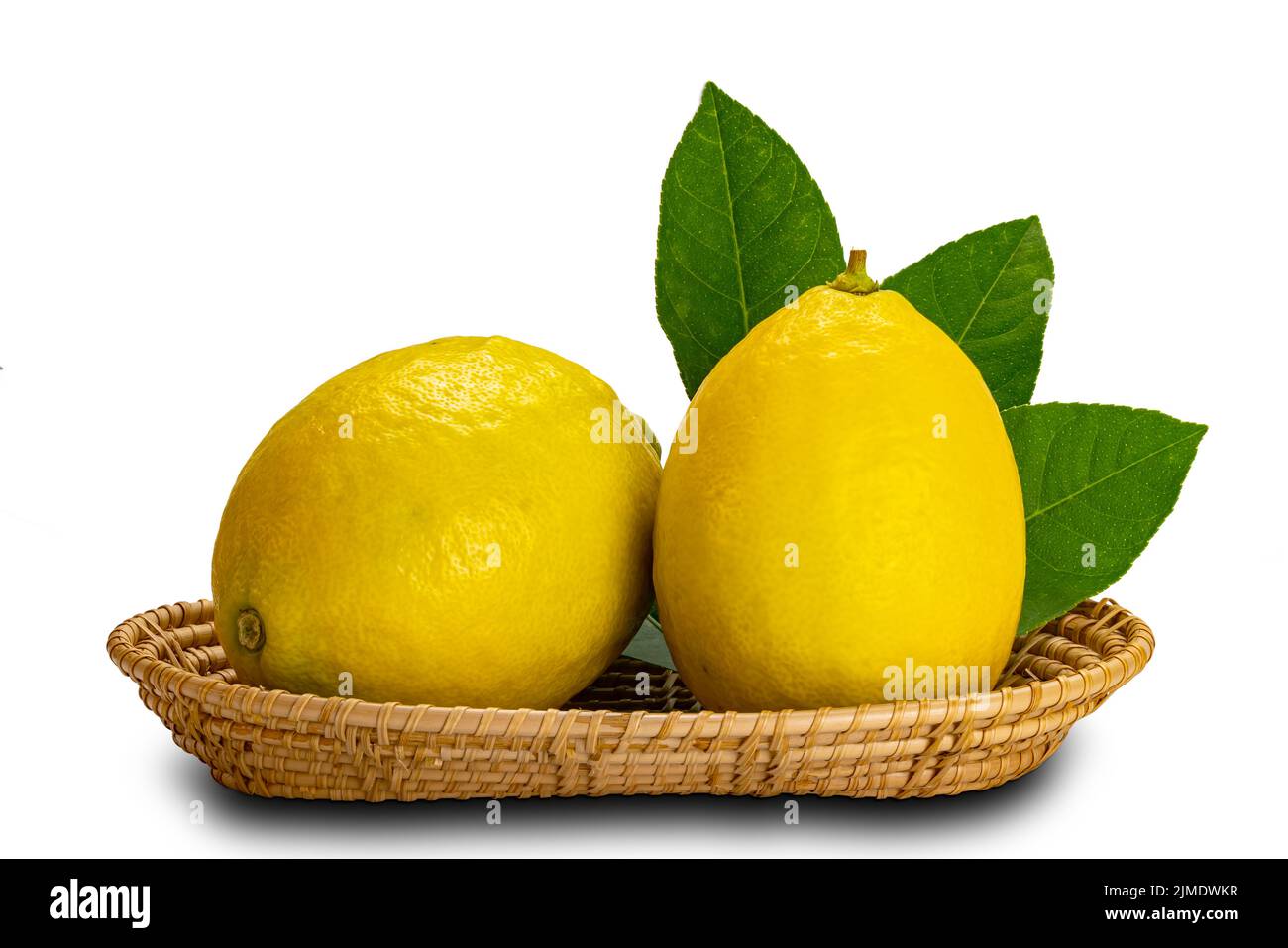 Citrons avec feuilles dans un plateau en bambou sur fond blanc. Banque D'Images