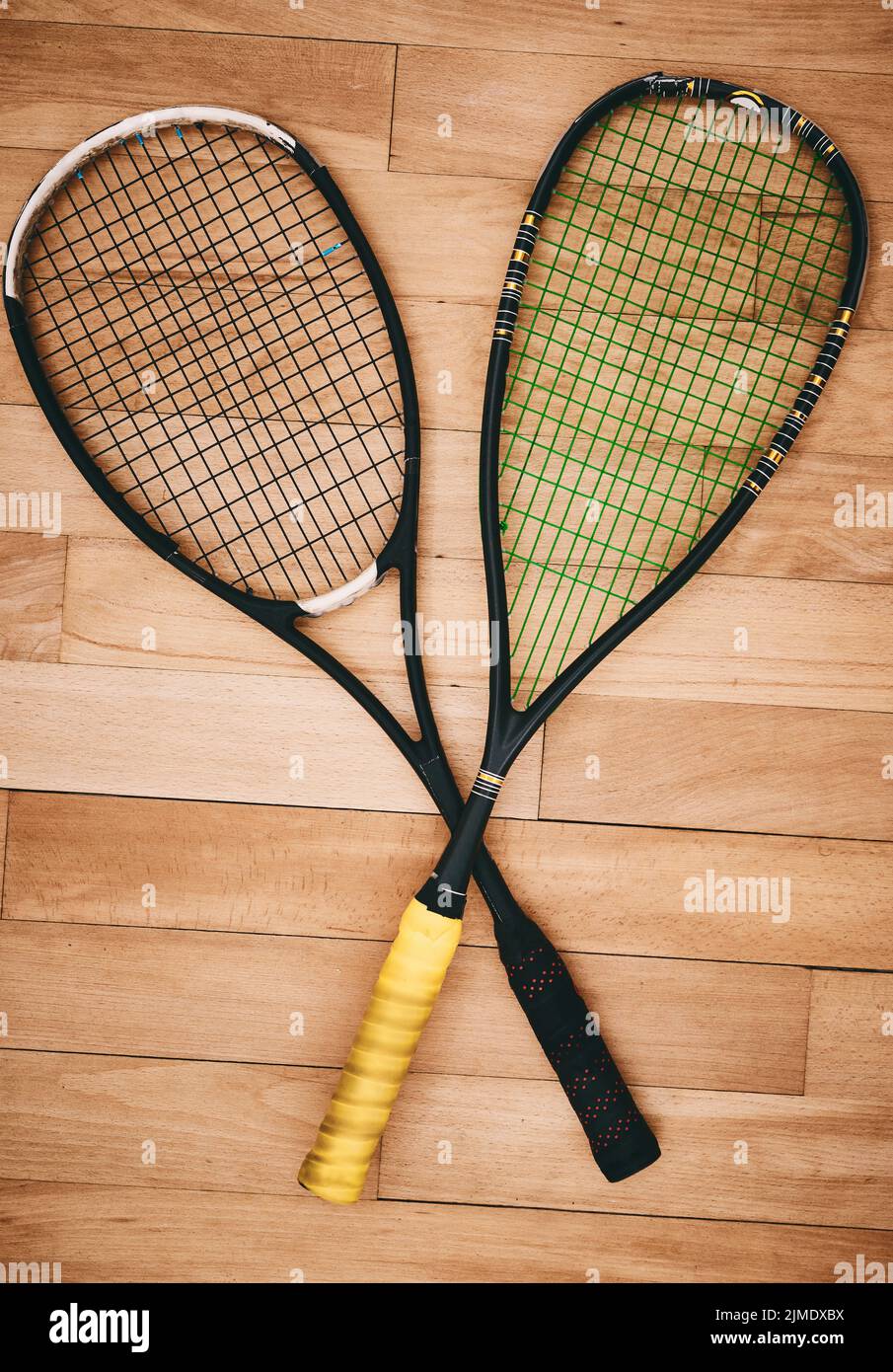 Une raquette de bonne qualité fait un bon jeu. Deux raquettes de squash sur le sol d'un court de squash. Banque D'Images