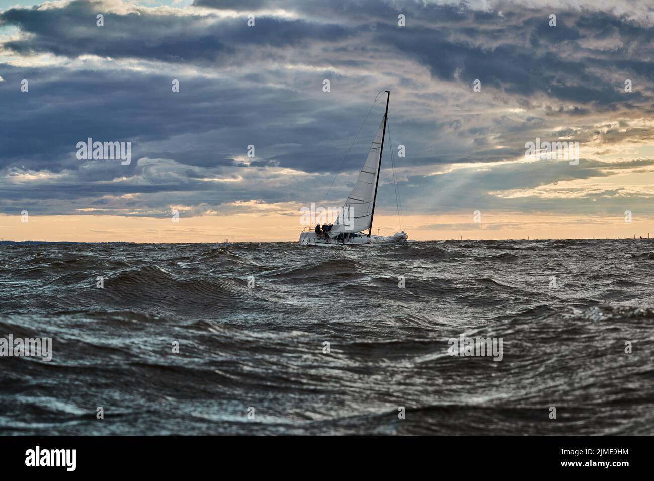 Le seul voilier à l'horizon en mer au coucher du soleil, le ciel de tempête de différentes couleurs, de grandes vagues, régate de voile, temps nuageux, Banque D'Images
