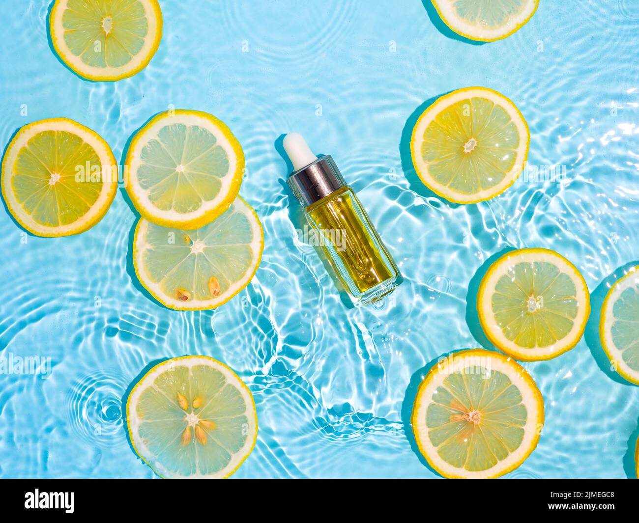 Bouteille cosmétique dans l'eau, tranches de citron, bleu Banque D'Images