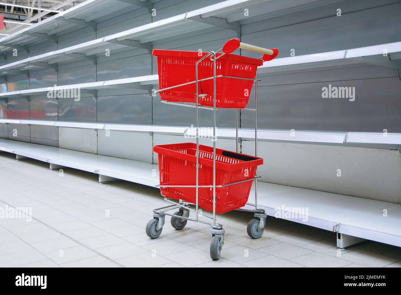 Chariot à provisions avec paniers vides contre des étagères vides dans l'épicerie Banque D'Images