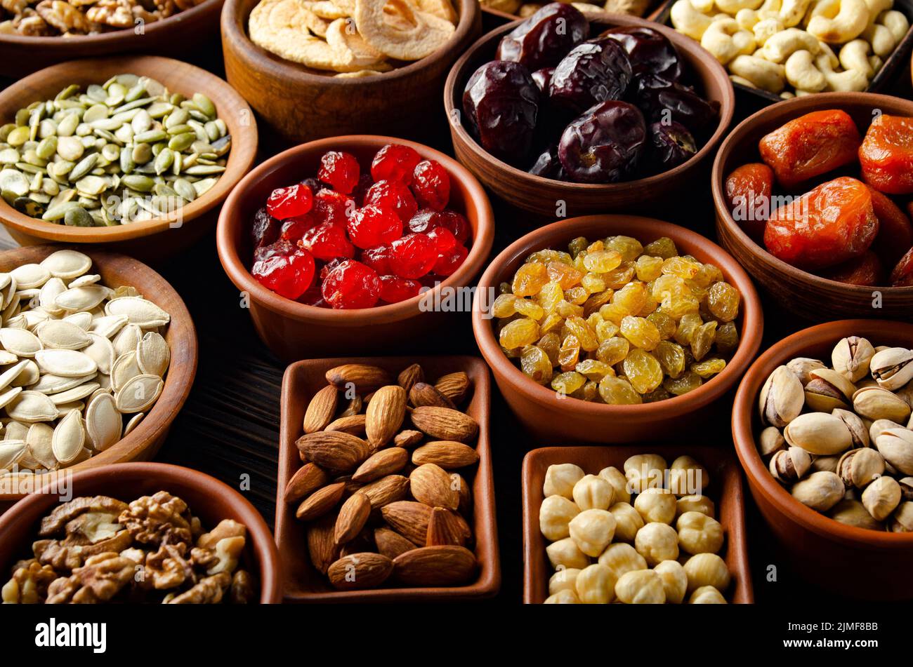 Assortiment de graines de noix et de fruits déshydratés dans des bols sur bois table de cuisine Banque D'Images