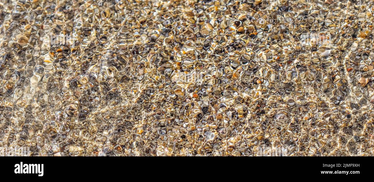 Un fond de sable, de petits cailloux et de vagues sur la plage. Concept de vacances d'été Banque D'Images