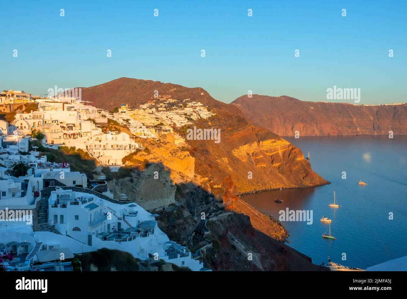 Maisons blanches à Oia et plusieurs bateaux garés près de Santorin lors d'une Sunny Day Banque D'Images