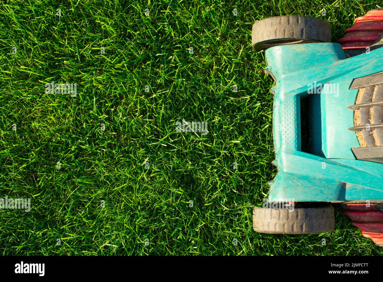 Tondeuse à gazon électrique sur fond d'herbe verte, vue de dessus Banque D'Images