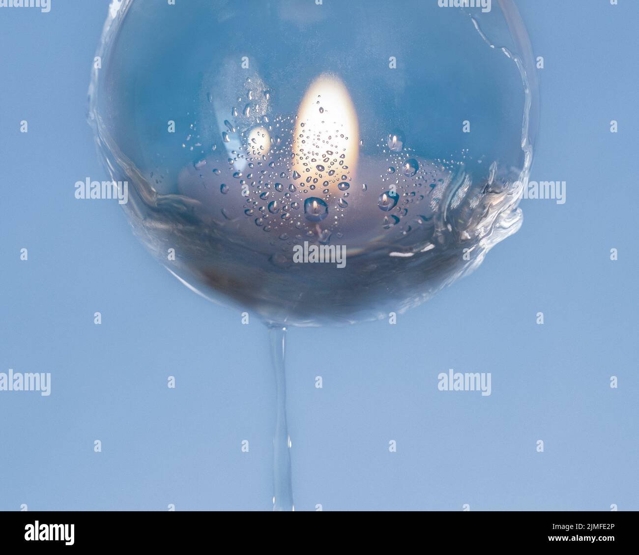 Une bougie vue à travers une boule d'objectif humide, placé sur un fond bleu, Royaume-Uni Banque D'Images