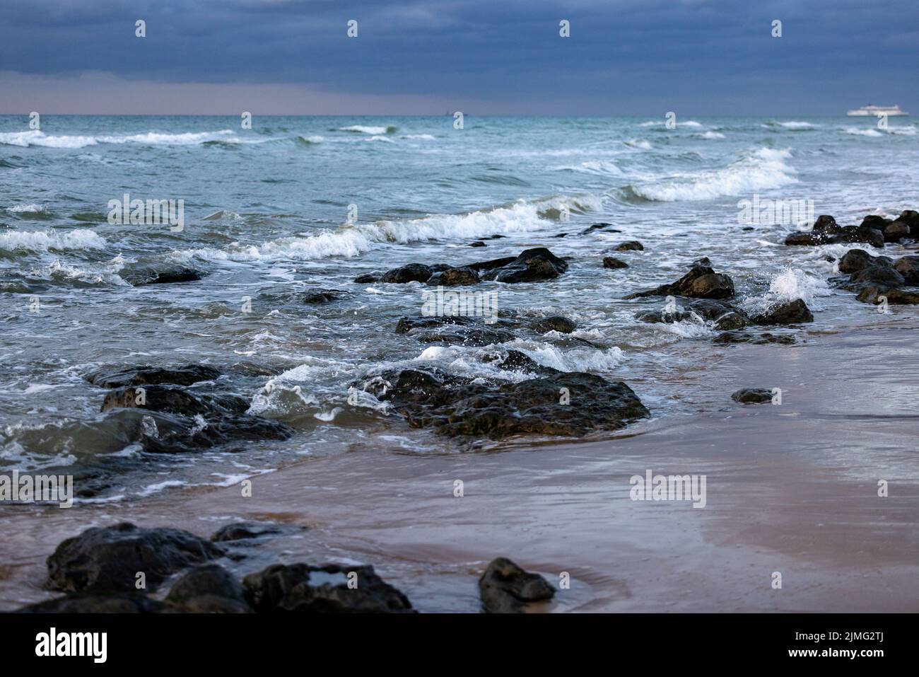 Les vagues de mer frappent des rochers sur la plage avec de l'eau de mer turquoise causant des éclaboussures d'eau. Paysage marin de falaise de roche incroyable en français Banque D'Images