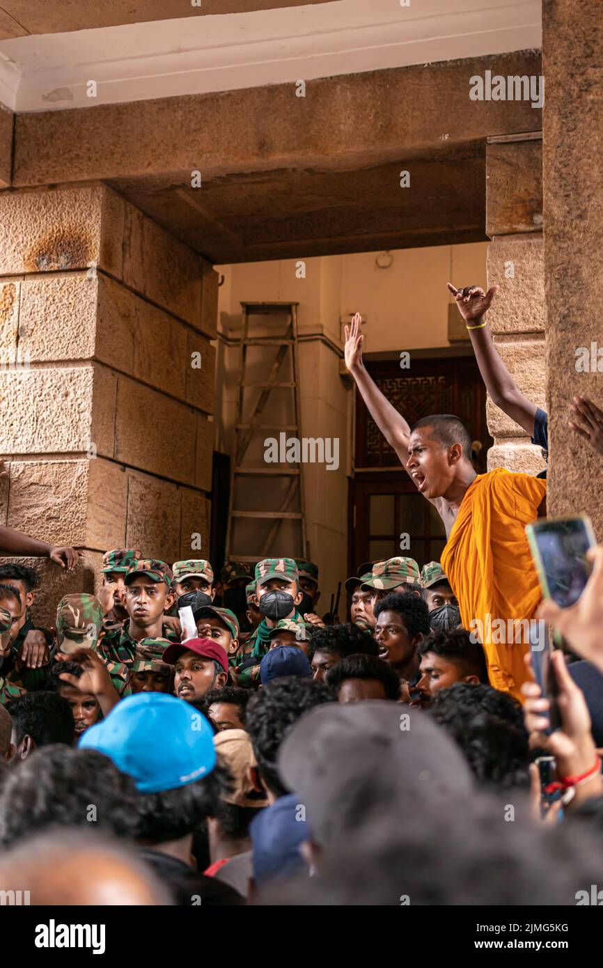 COLOMBO, SRI LANKA: 9th juillet 2022: Le moine bouddhiste en robe de safran se dresse au-dessus d'une foule de manifestants et de soldats en colère au Secrétariat présidentiel. Banque D'Images