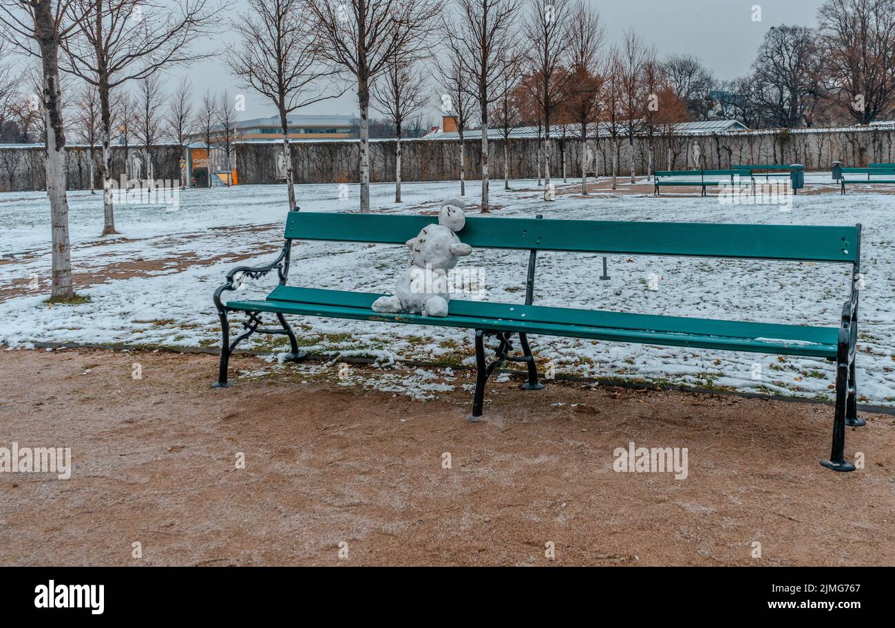 Bonhomme de neige assis sur un banc dans un parc public Banque D'Images