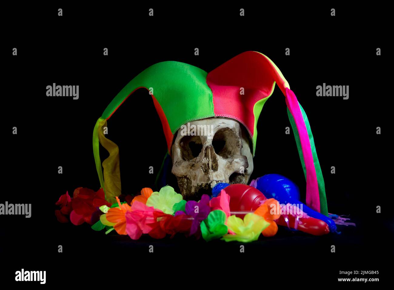 Crâne humain avec chapeau d'arlequin et éléments de fête Banque D'Images