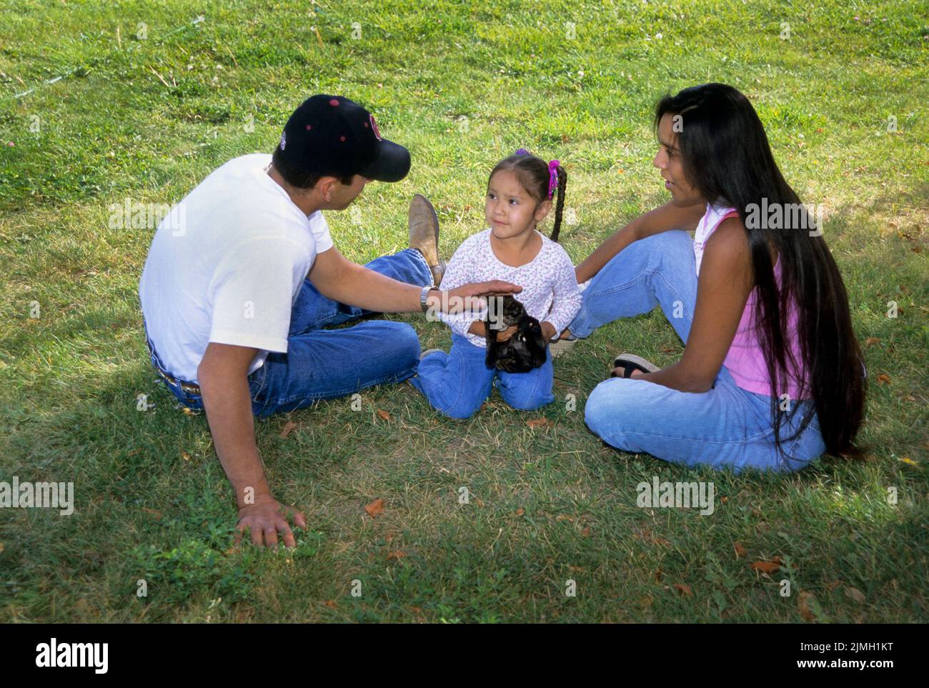 La famille américaine autochtone de trois enfants joue avec un chaton d'animal de compagnie. Les parents enseignent à la jeune fille comment prendre soin de son animal de compagnie. Fort Hall Idaho Banque D'Images