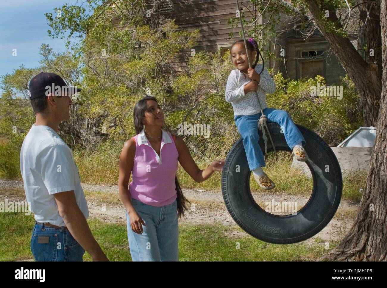 Shoshone Bannock parents avec une jeune fille jouant sur une balançoire de pneu, fort Hall Idaho Banque D'Images
